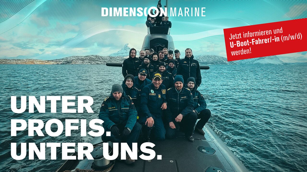 Mehrere Personen posieren auf einem U-Boot welches im Meer schwimmt.