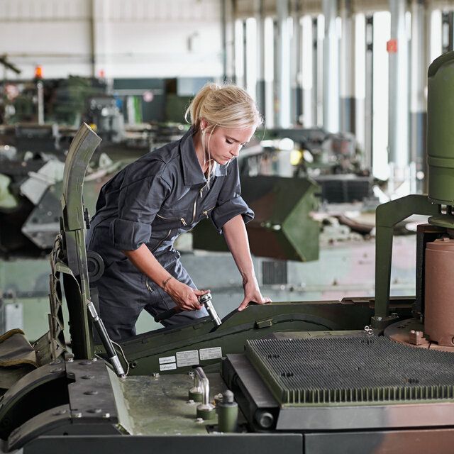 Eine Technikerin führt Montagearbeiten an einem Schützenpanzer durch.