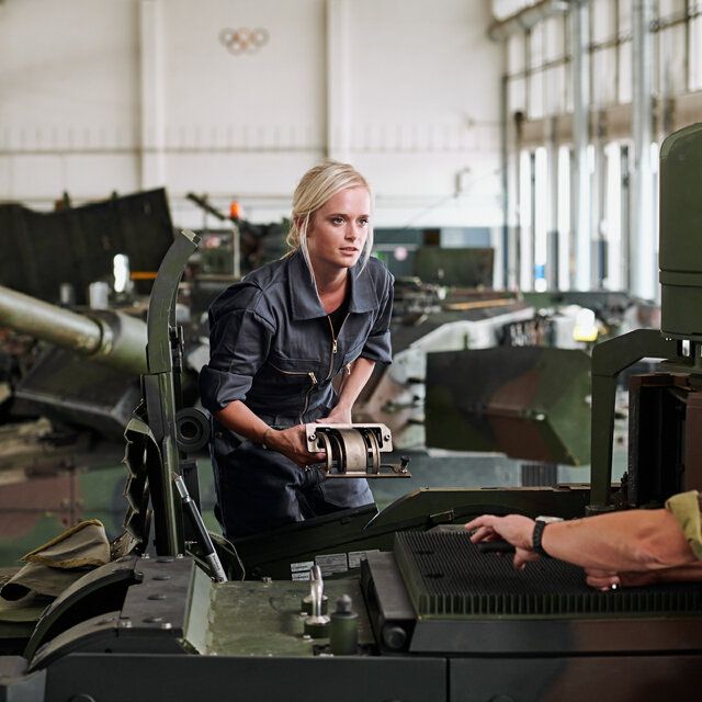 Eine Technikerin im Gespräch mit einem Soldaten in der Montagehalle