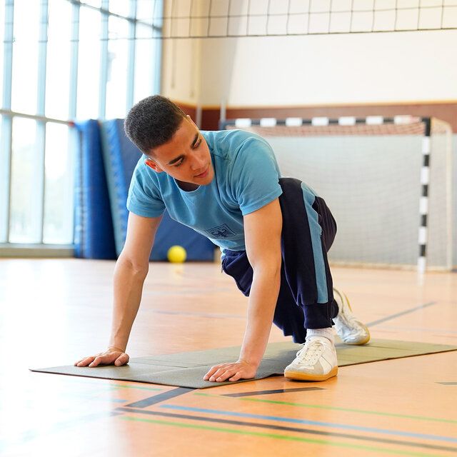 Ein Soldat in Sportkleidung macht sportliche Übungen in einer Turnhalle